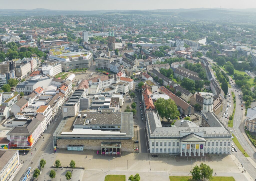 Luftaufnahme von Kassel mit Blick auf die Innenstadt, die documenta-Halle und das Fridericianum, umgeben von Wohngebieten, Grünflächen und der Fulda.